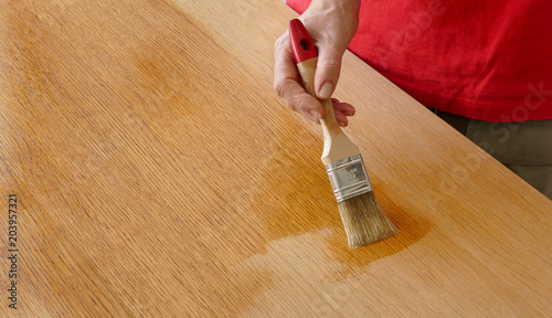 Foto Wooden plank varnishing, workers hand using tool, paint brush