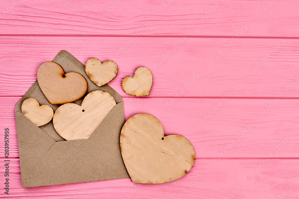 Plywood hearts, envlope and copy space. Blank wooden hearts with hole and envelope on colorful wooden background, text space.