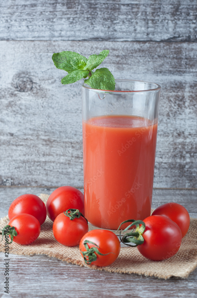 Close-up of a glass of tomato juice with vegetables on wooden sacking background. Vitamins and minerals. Healthy drink concept. Close-up of a glass of tomato juice with vegetables on wooden sacking background. Vitamins and minerals. Healthy drink concept.