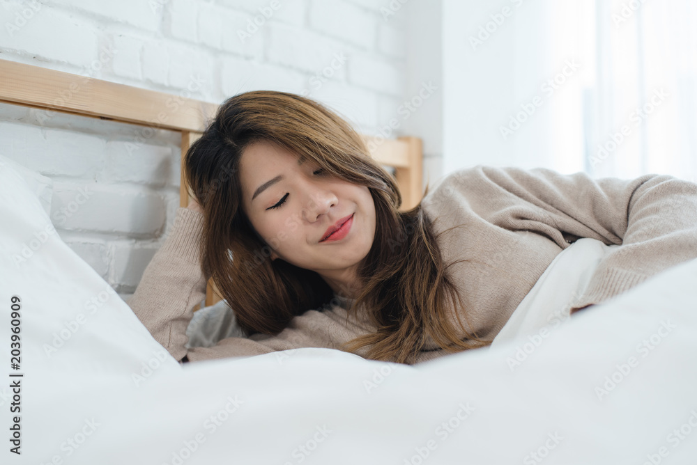Portrait beautiful young Asian woman on bed at home in the morning. Cheerful Asian woman wearing a comfortable sweater and smiling on her bed. Relaxing room. lifestyle asia woman at home concept. Portrait beautiful young Asian woman on bed at home in the morning. Cheerful Asian woman wearing a comfortable sweater and smiling on her bed. Relaxing room. lifestyle asia woman at home concept.