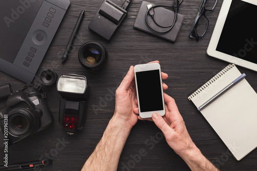 Photographer using smartphone on workplace