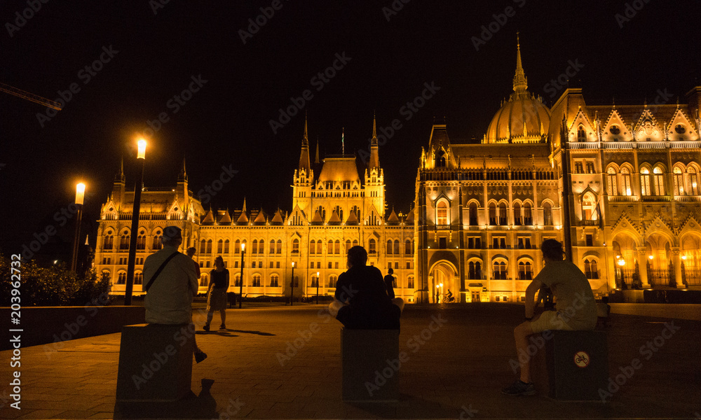 Leute nachts vor dem Parlament in Budapest.