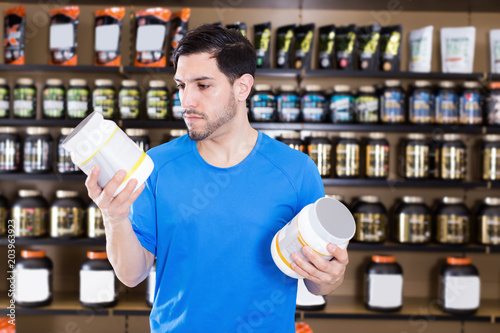 Attractive sport man looking different sport nutrition products