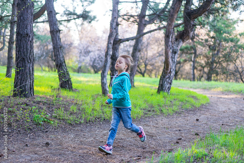Little girl runing along the forest path, a bright photo of spring.