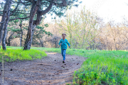 Little girl runing along the forest path, a bright photo of spring.