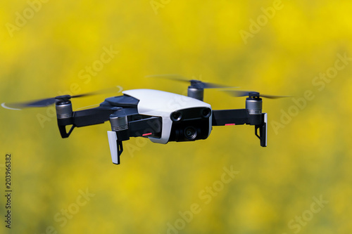 mini drone floating above rapeseed yellow field recording videos and taking pictures