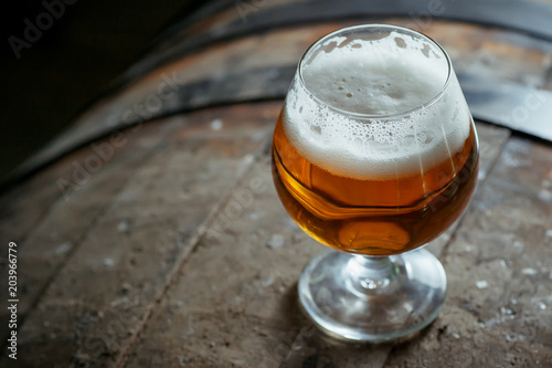 Tablou pe pânză Snifter beer glass on a wooden barrel