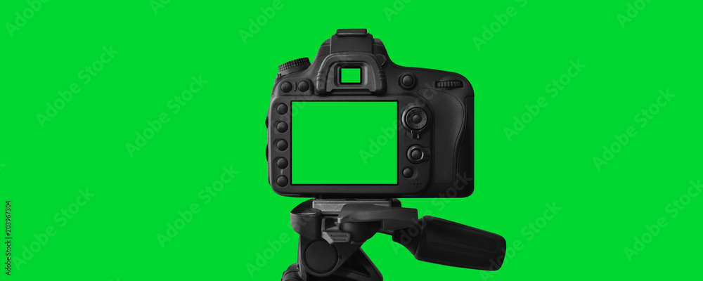 Obraz premium The Dslr camera with empty screen on the tripod, isolated on green background. The chromakey. Green screen.
