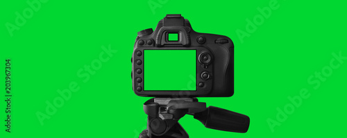 The Dslr camera with empty screen on the tripod, isolated on green background. The chromakey. Green screen. photo