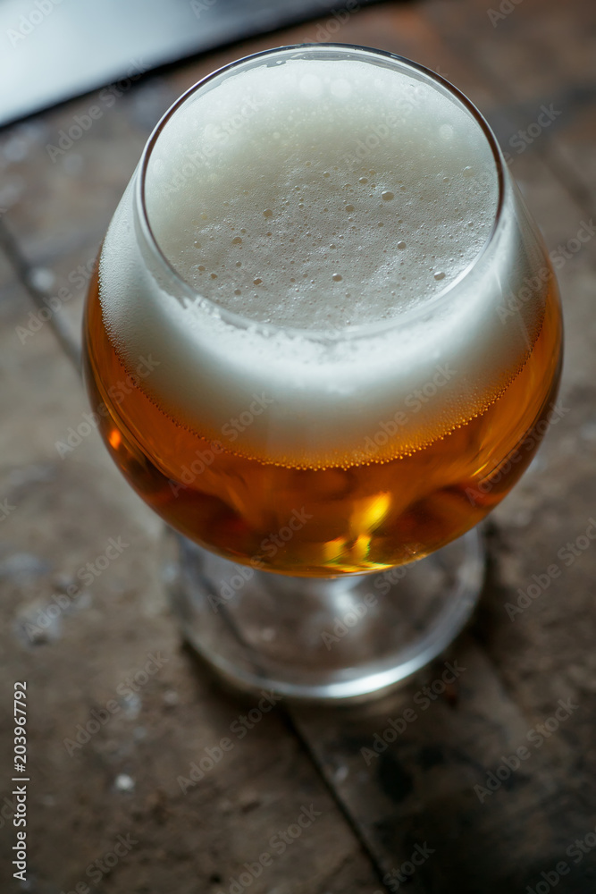 Snifter beer glass on a wooden barrel