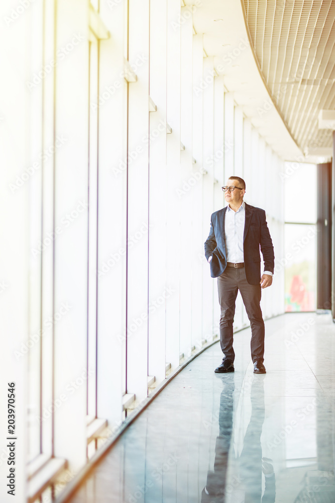 full length picture of a mid aged business man walking towards the camera and smiling in office building