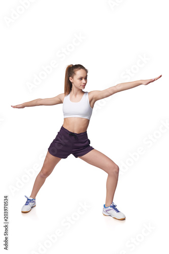 Full length teen girl smiling doing fitness exercises, isolated on white background