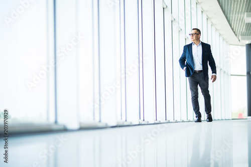 Handsome and sucessful senior business man walking in modern office interior