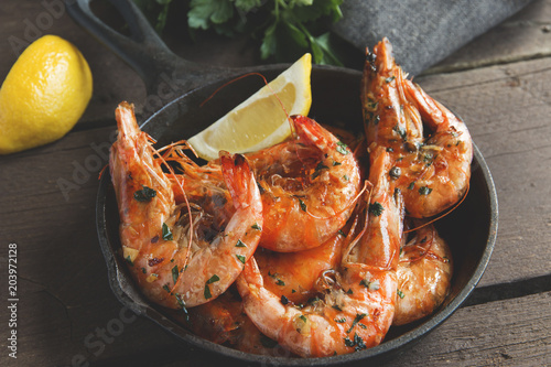 fried roasted shrimps in frying pan with lemon greens parsley garlic