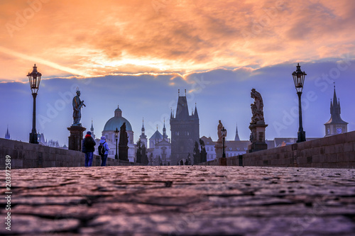 Charles Bridge in the old town of Prague at sunrise with cobble stone pavements and dramatic sky