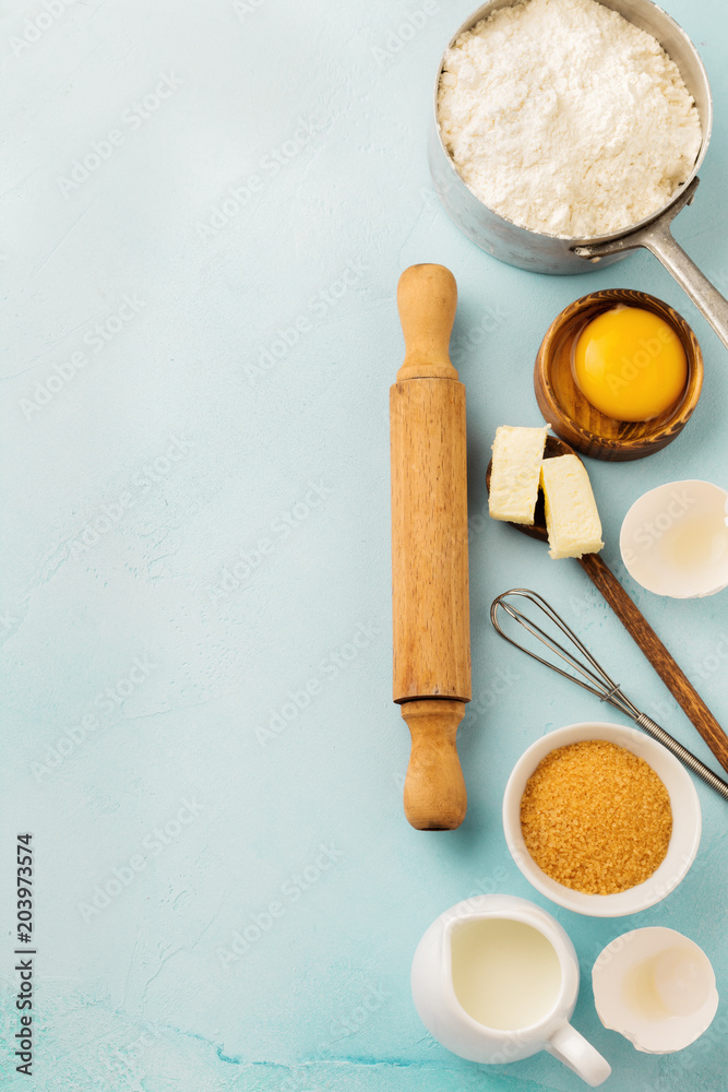 Baking background with ingredients flour, eggs, sugar, butter, cinnamon, anise star and kitchen tools on blue rustic table. Selective focus. Top view. Baking background with ingredients flour, eggs, sugar, butter, cinnamon, anise star and kitchen tools on blue rustic table. Selective focus. Top view.