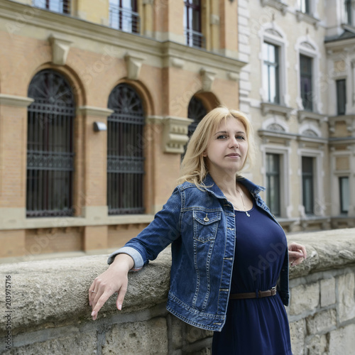 Young beautiful blonde model girl in the old town in the spring.