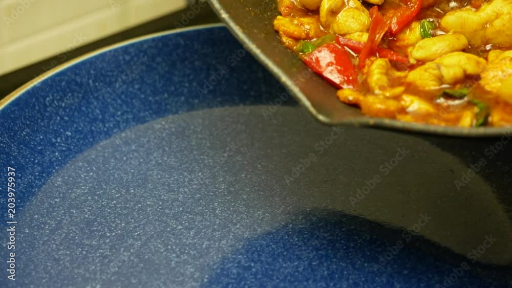 pour stir fried chicken with spicy curry paste , sweet basil, bell pepper, long yard beans , sliced corn from black teflon pan into blue dish