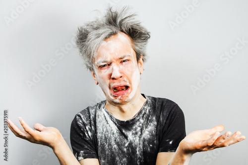 Konstfotografi Unshorn and unshaven young guy soiled in plaster or flour and cry, on gray background