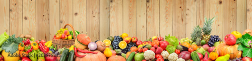 Panoramic photo healthy vegetables and fruits against light wooden wall.
