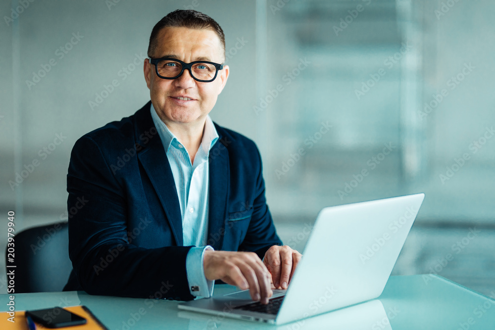 Positive Business Leader Sitting at Desk in modern office Positive Business Leader Sitting at Desk in modern office