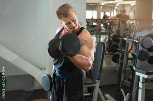 handsome young man in training with dumbbells in the gym