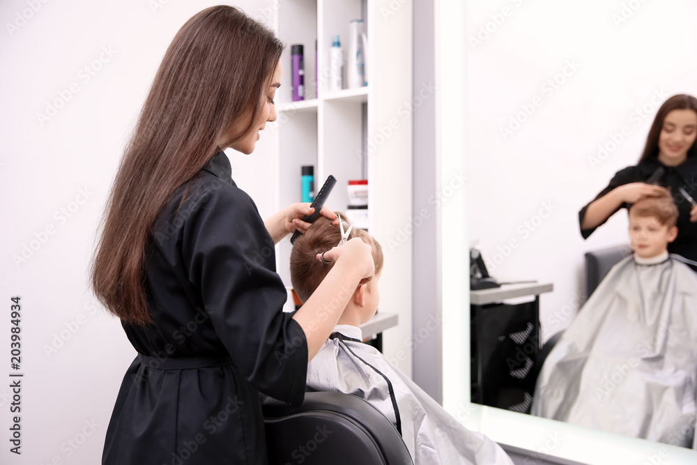 Professional female hairdresser working with little boy in salon Professional female hairdresser working with little boy in salon