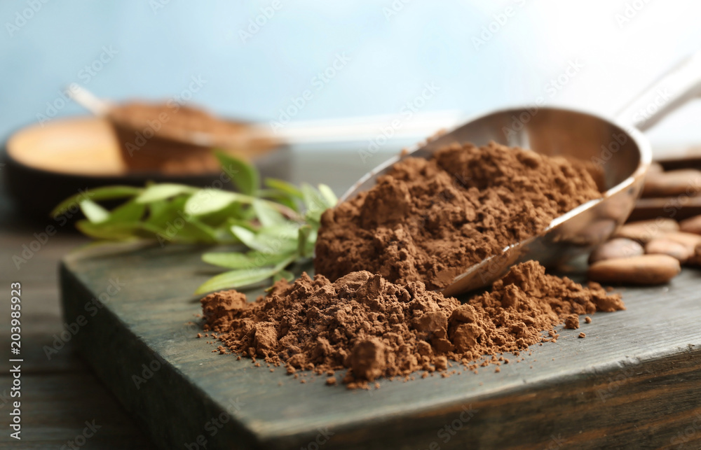 Scoop with cocoa powder on wooden board Scoop with cocoa powder on wooden board