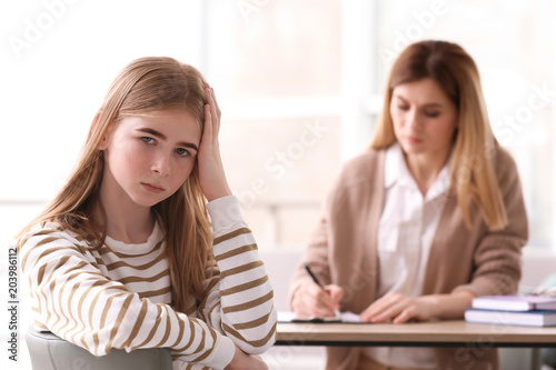 Young female psychologist working with teenage girl in office