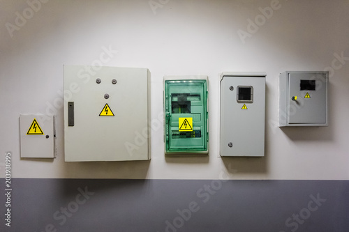 Photos Metal and plastic electric breaker boxes with yellow electrical warning signs of