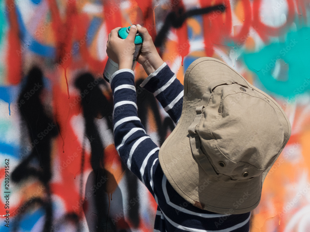 Young artist painting graffiti wall bright colours background Young artist painting graffiti wall bright colours background