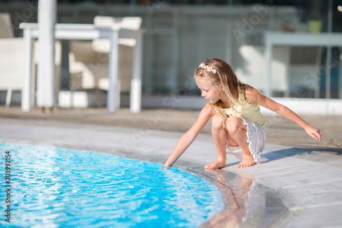 Little girl having fun with a splash near swimming pool