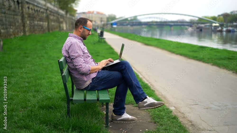 Young man sitting with laptop on bench in the park
Young man sitting with laptop on bench in the park