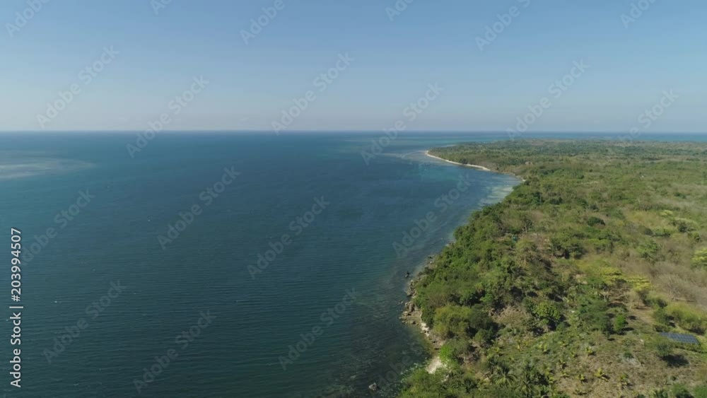 Aerial view of Coastline landscape with rocky beach with palm trees, blue water on tropical island. Flight over a wild beach. Philippines, Luzon. Aerial view of Coastline landscape with rocky beach with palm trees, blue water on tropical island. Flight over a wild beach. Philippines, Luzon.