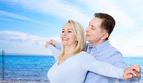 Beach couple laughing in love romance on travel honeymoon vacation summer holidays romance. Middle aged happy people, woman and man embracing outdoors on tropical beach in casual wear.