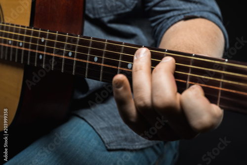 male hands play acoustic guitar
