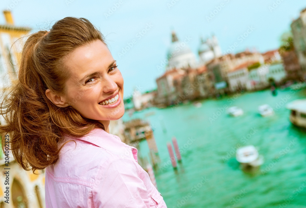 Naklejka premium Happy young woman standing on bridge with grand canal view in venice, italy