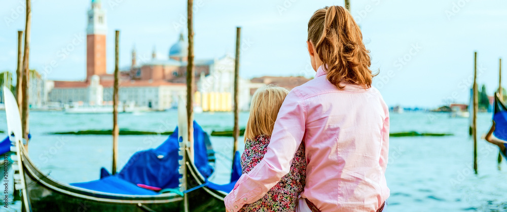 Fototapeta premium mother and baby sitting on grand canal embankment in