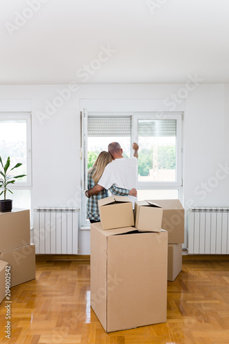 Happy middle aged couple with boxes moving into new home or apartment. Real estate theme. © Dusko