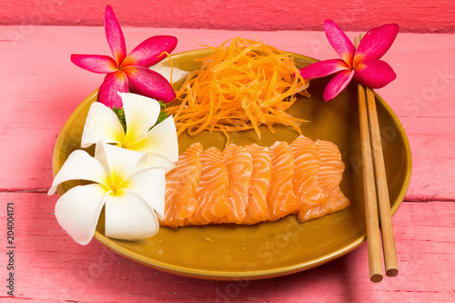 Salmon sashimi on dish with flower on wood color pink