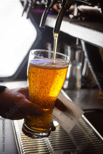 The bartender pours fresh light lager