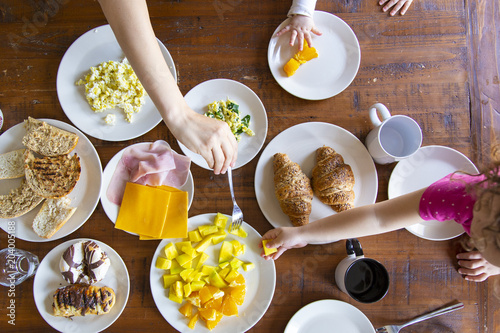 Family havind several dishes for brakfast on a wooden table photo