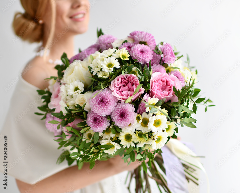 Naklejka premium Beautiful woman hold bouquet of chrysanthemum and roses flowers white and purple happy smiling on grey 