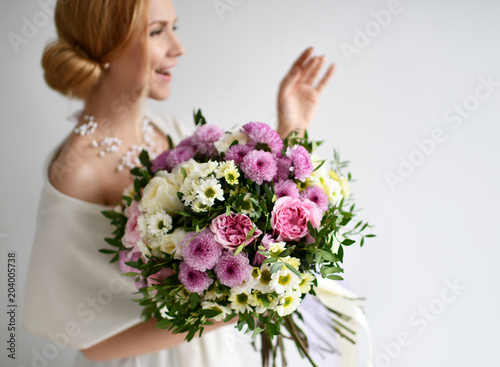 Beautiful woman hold bouquet of chrysanthemum and roses flowers white and purple happy smiling on grey 