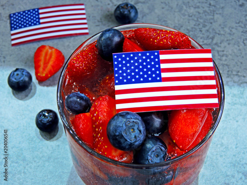 A festive lemonade with strawberries and blueberries on Independence Day. Soda in patriotic style. American flags.