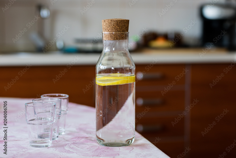 Fresh water with lemon. A refreshing drink in a glass container standing in the kitchen. Fresh water with lemon. A refreshing drink in a glass container standing in the kitchen.