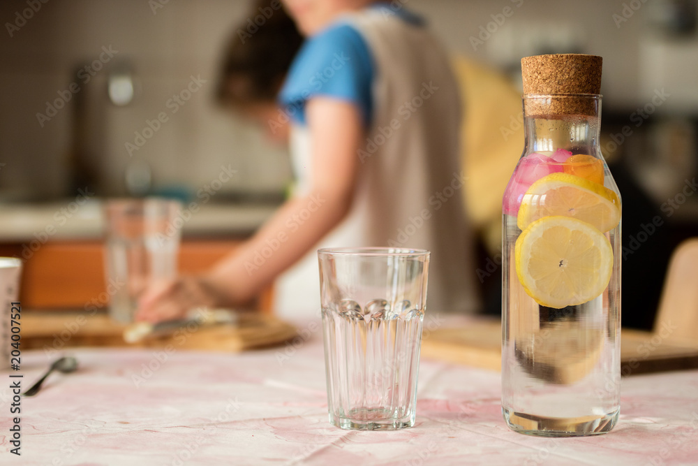 Fresh water with lemon. A refreshing drink in a glass container standing in the kitchen.