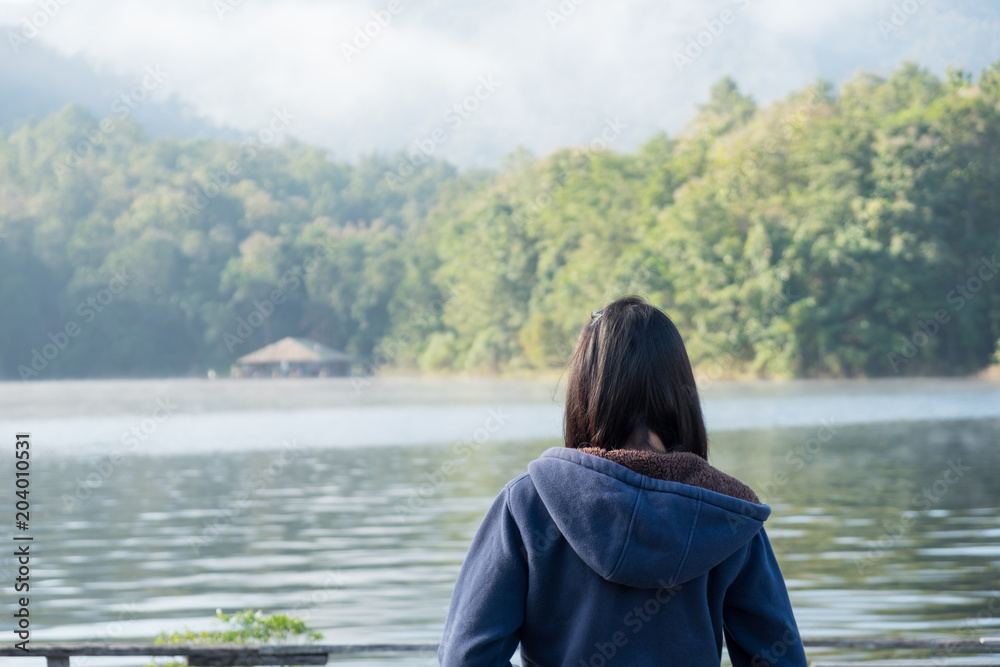 The girl watches the lake in the morning.