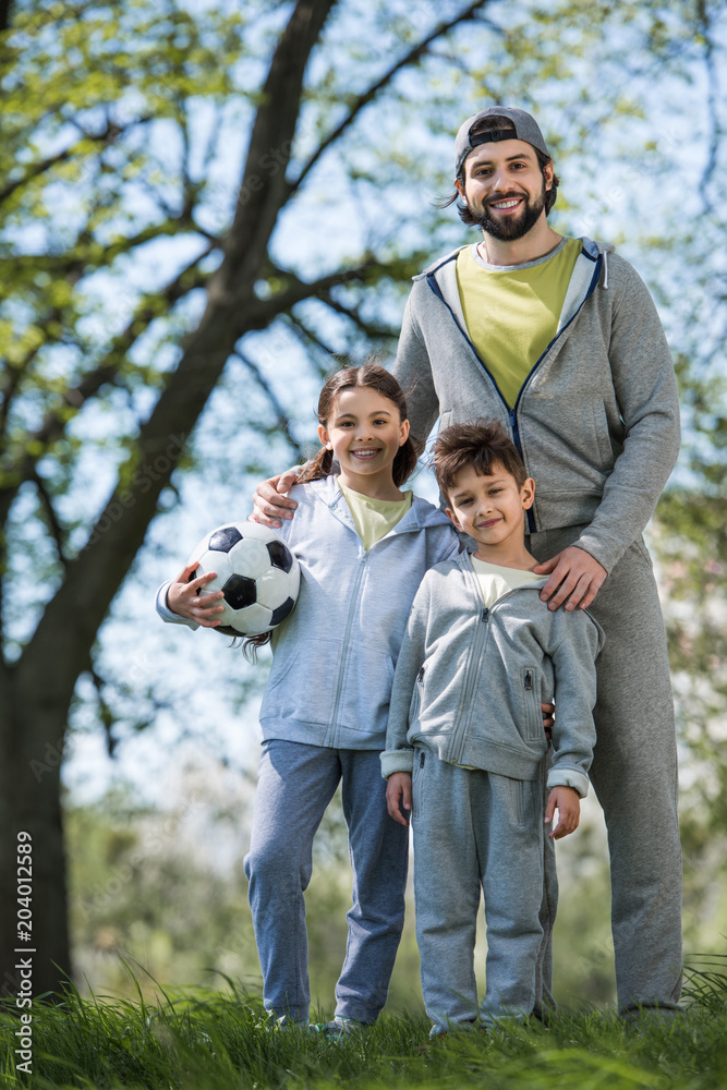 happy family with soccer ball standing in park happy family with soccer ball standing in park