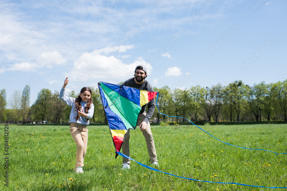 happy daughter and father with kite on meadow in park happy daughter and father with kite on meadow in park